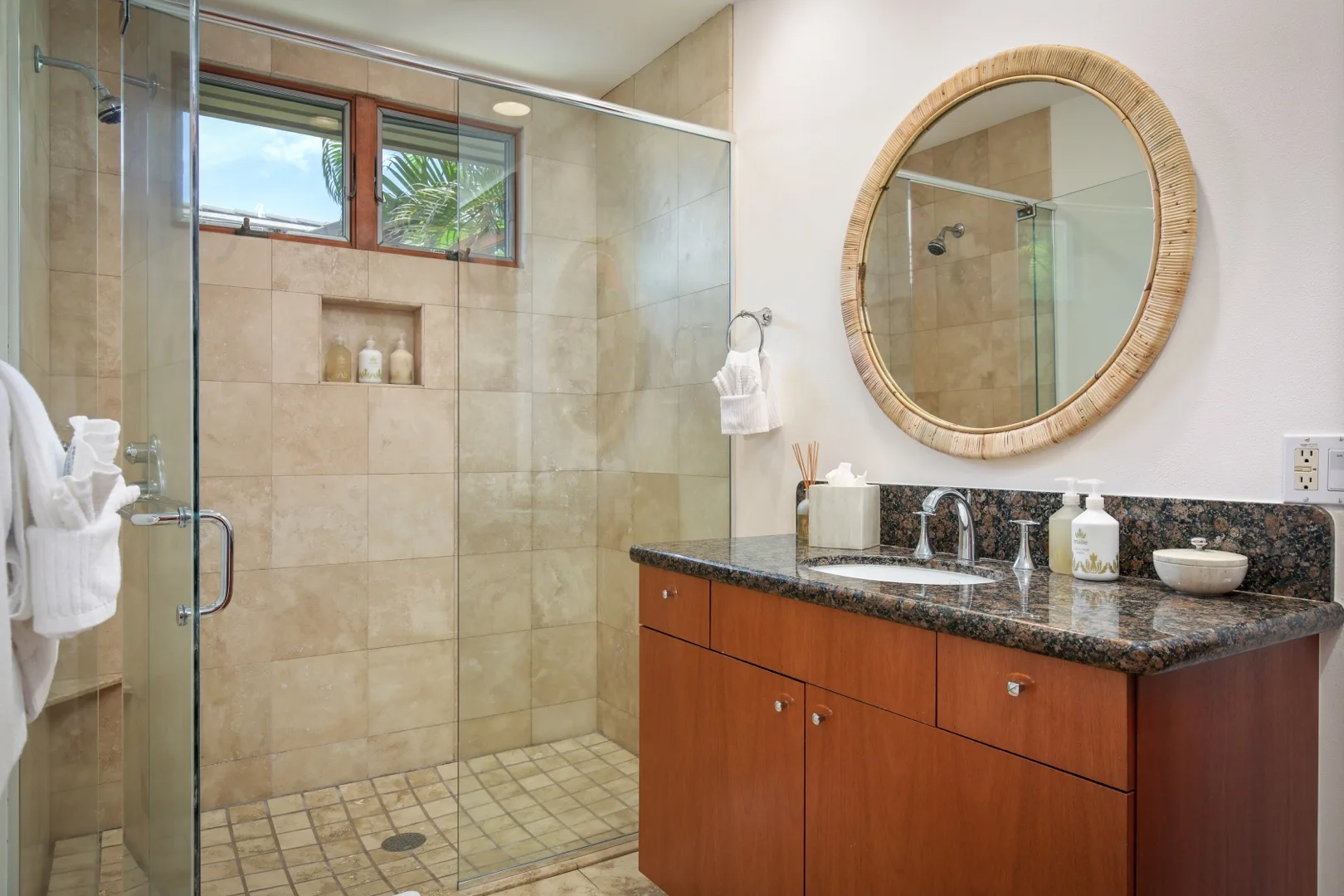 A bathroom with a glass shower, tiled walls, and a wood vanity.