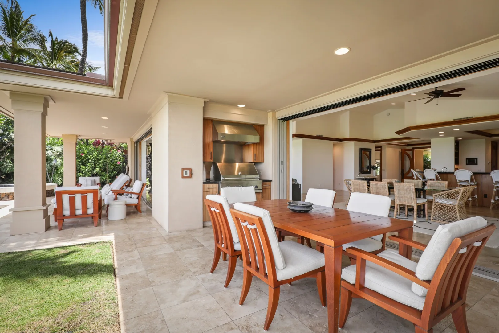 An open-air dining area with a wooden table and seating beside a garden patio.
