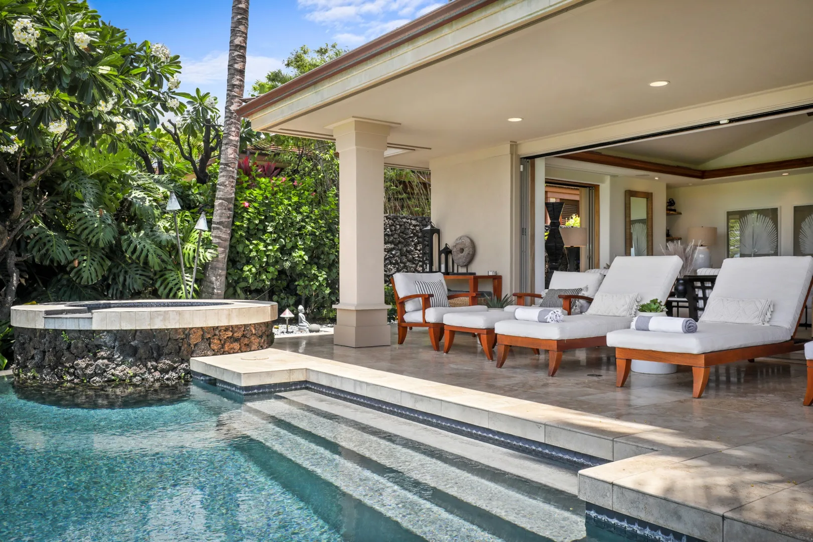 Una piscina exterior junto a un patio cubierto con asientos de descanso.