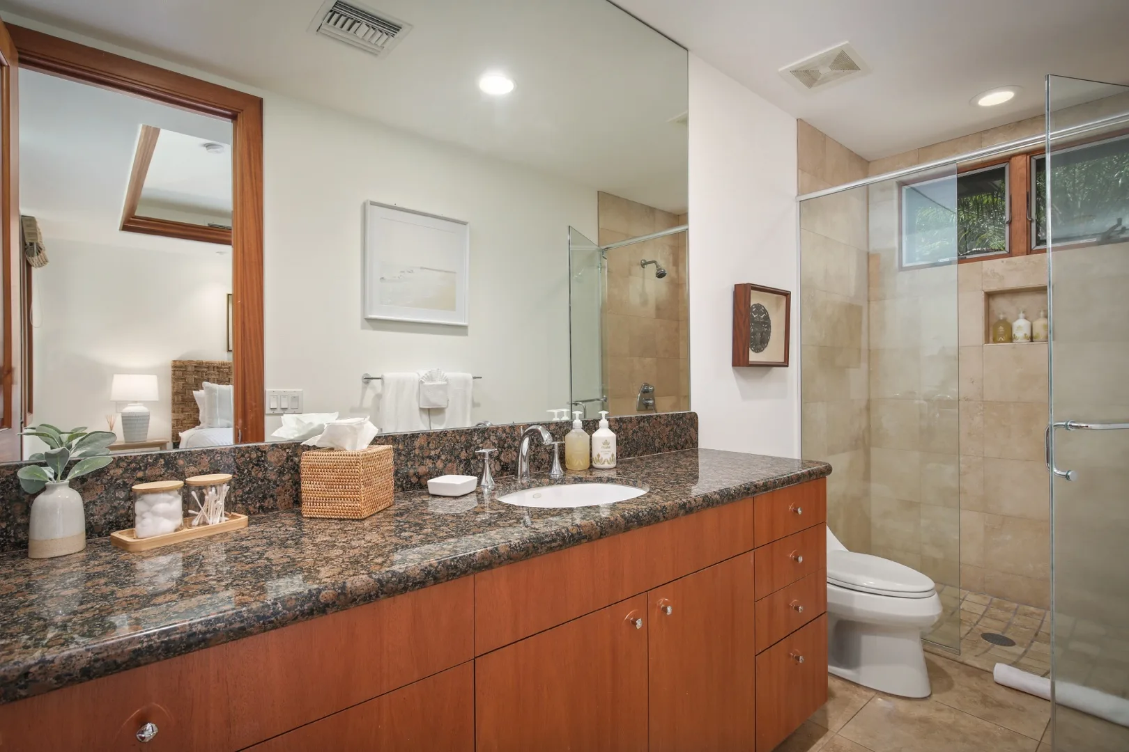A bathroom vanity with a long countertop and a glass-enclosed shower.