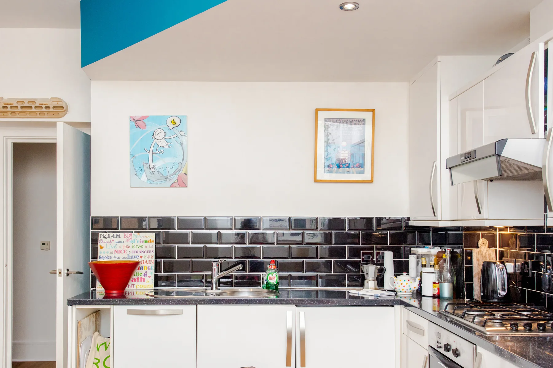 A compact kitchen with black tile backsplash, white cabinets, and a countertop.