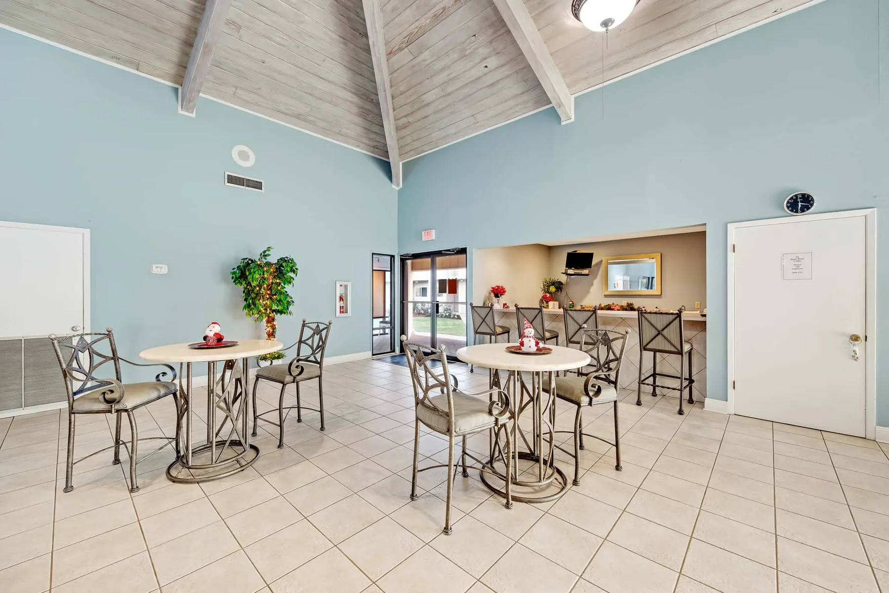 A shared dining area with round tables and chairs beside a counter.