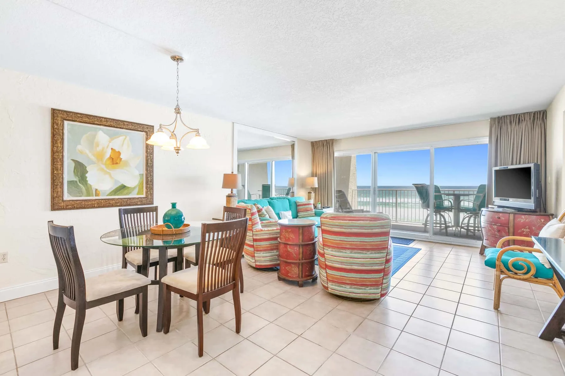 A living and dining area opens onto a balcony through broad glass doors.