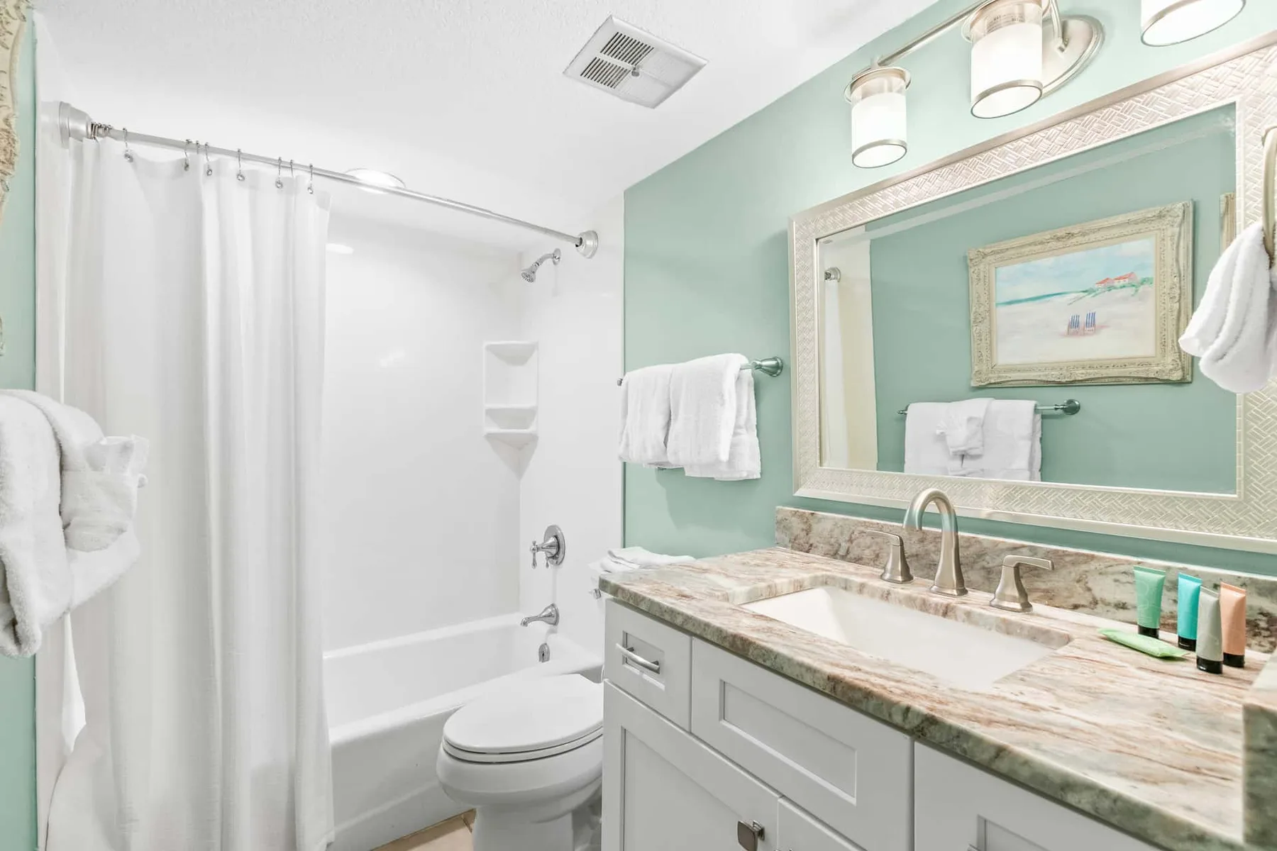 A bathroom with a vanity, mirror, and shower curtain.