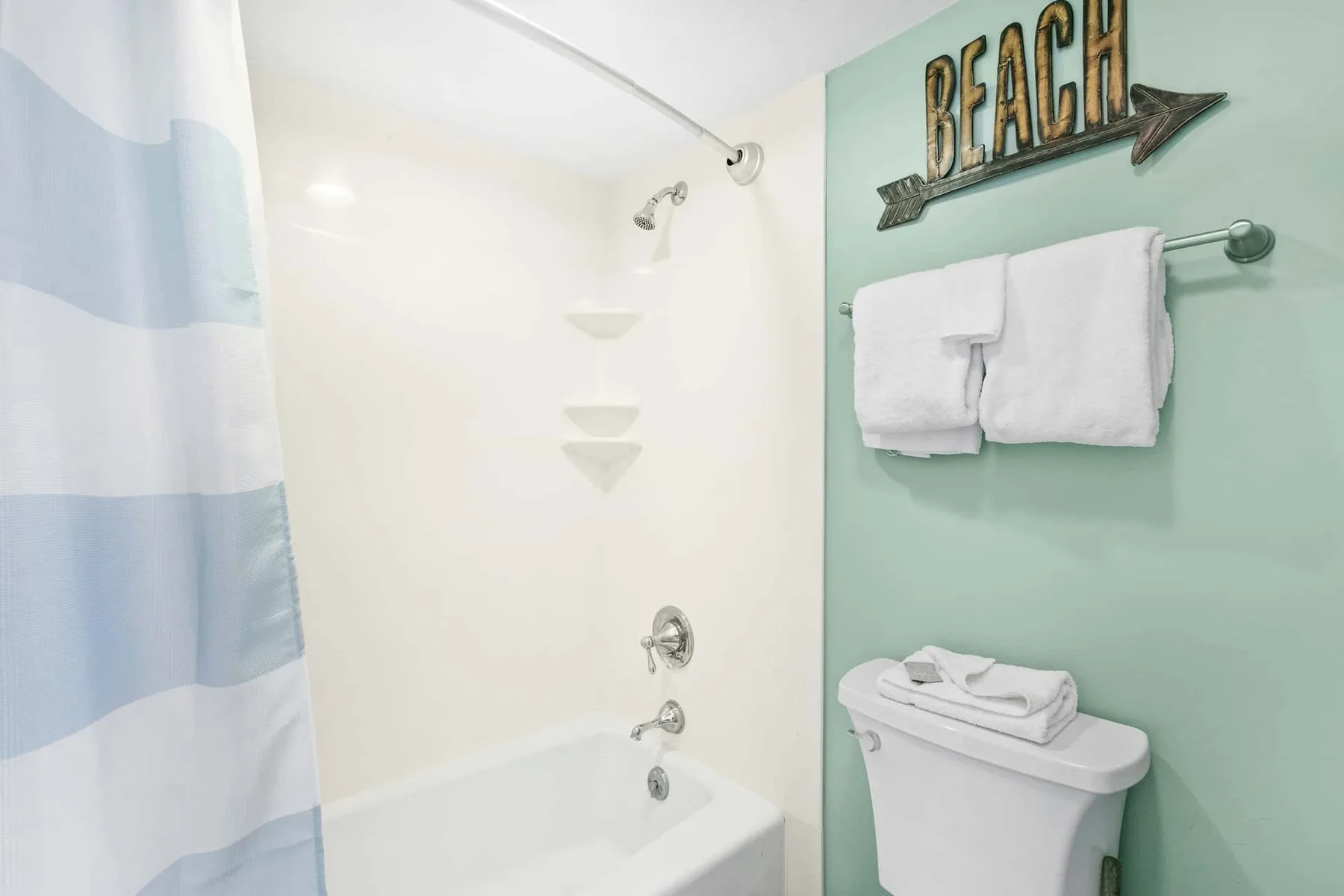 A bathroom with a bathtub, striped shower curtain, and towels hanging on the wall.