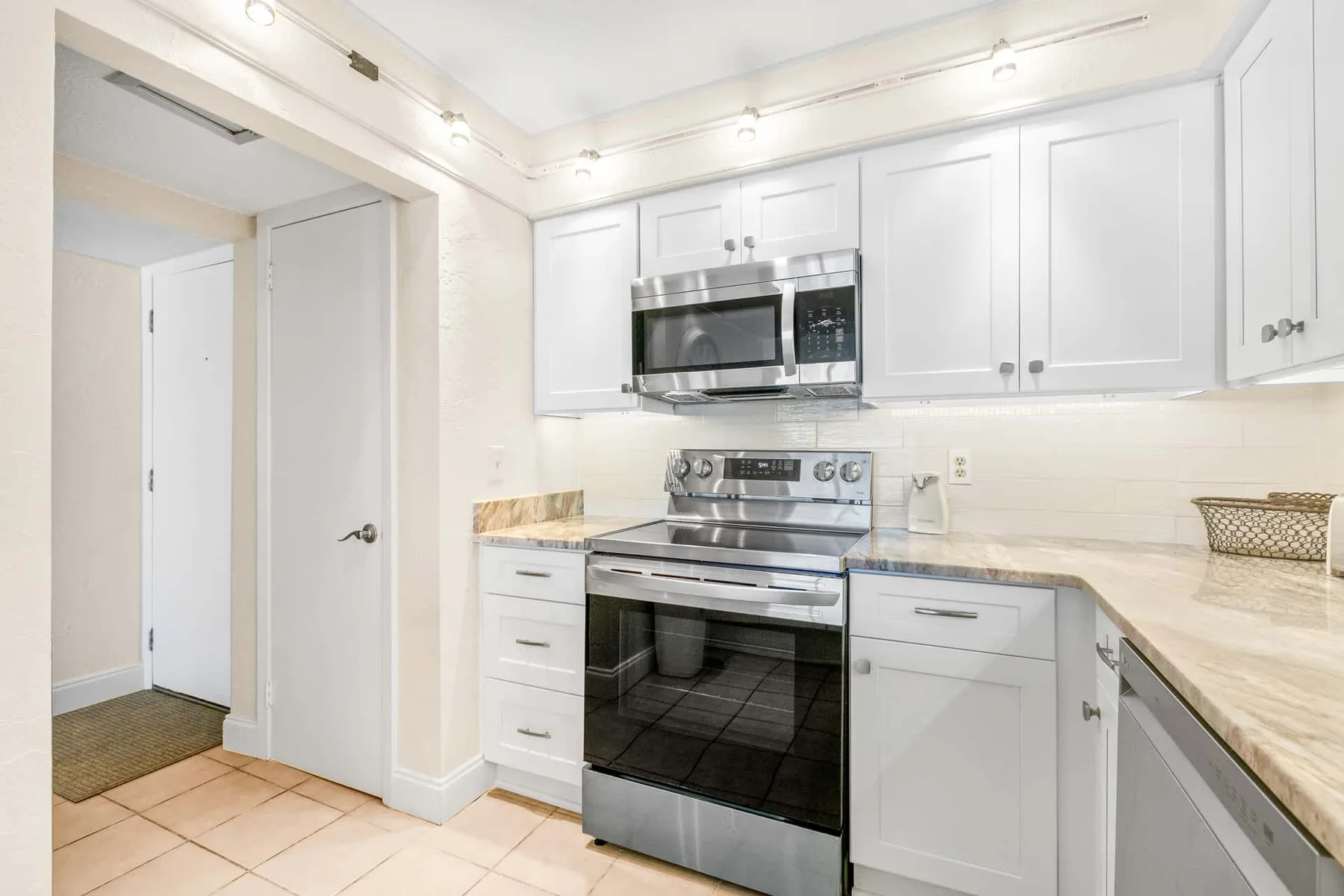A bright kitchen with white cabinets, a microwave, and a stainless-steel range.