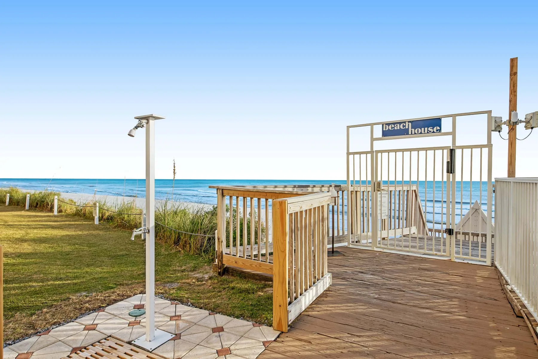 A wooden beachside deck opens toward the ocean, with a fenced walkway.