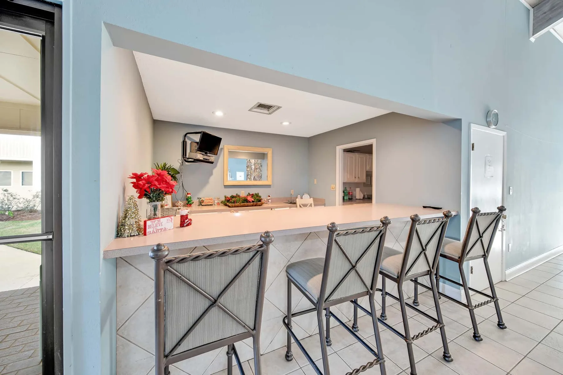 A counter with seating and a small television in a bright interior.