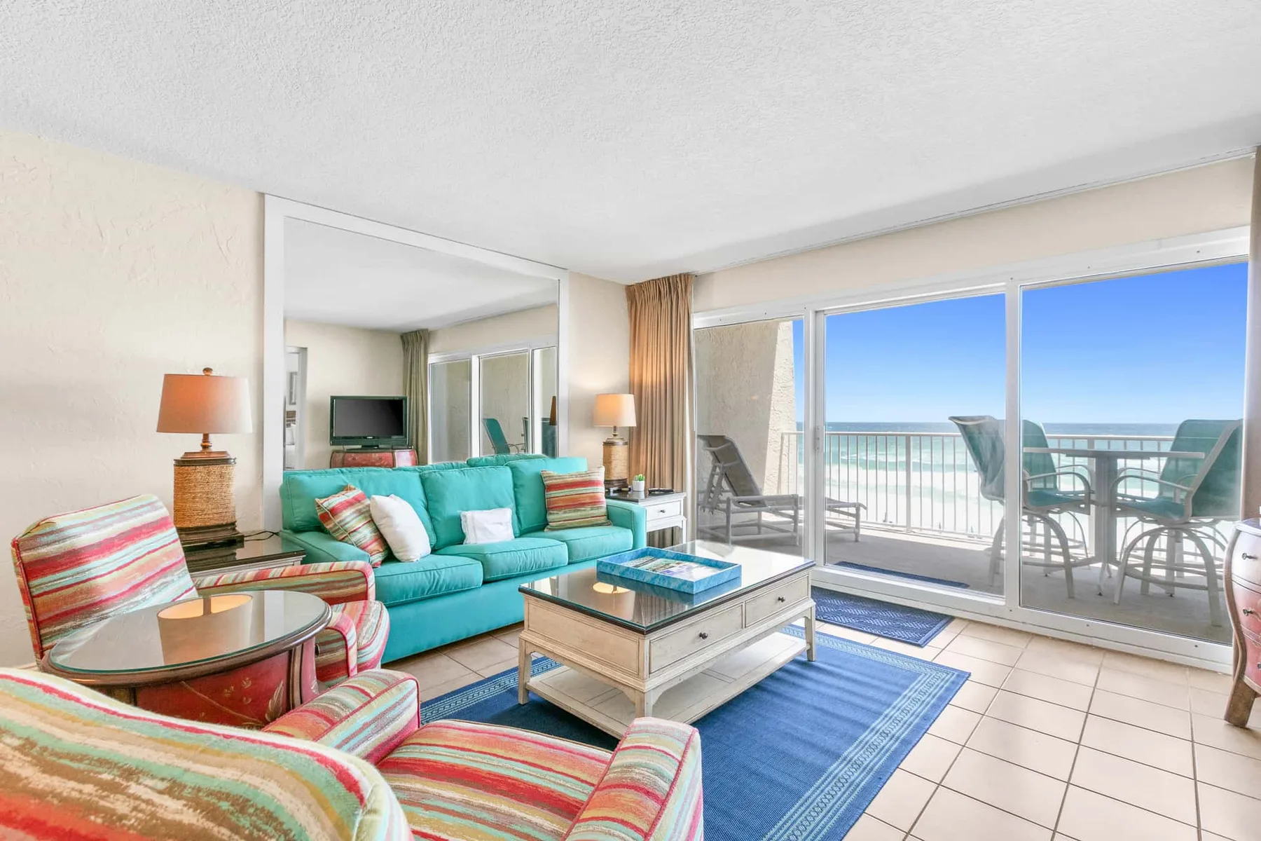 A living room with colorful seating and sliding glass doors opening onto a balcony.