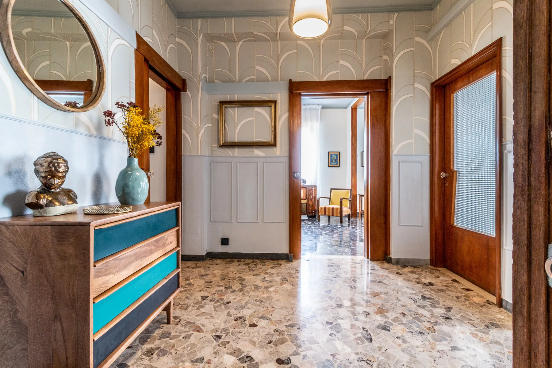 Un pasillo interior decorado con puertas de madera y suelo de baldosas.