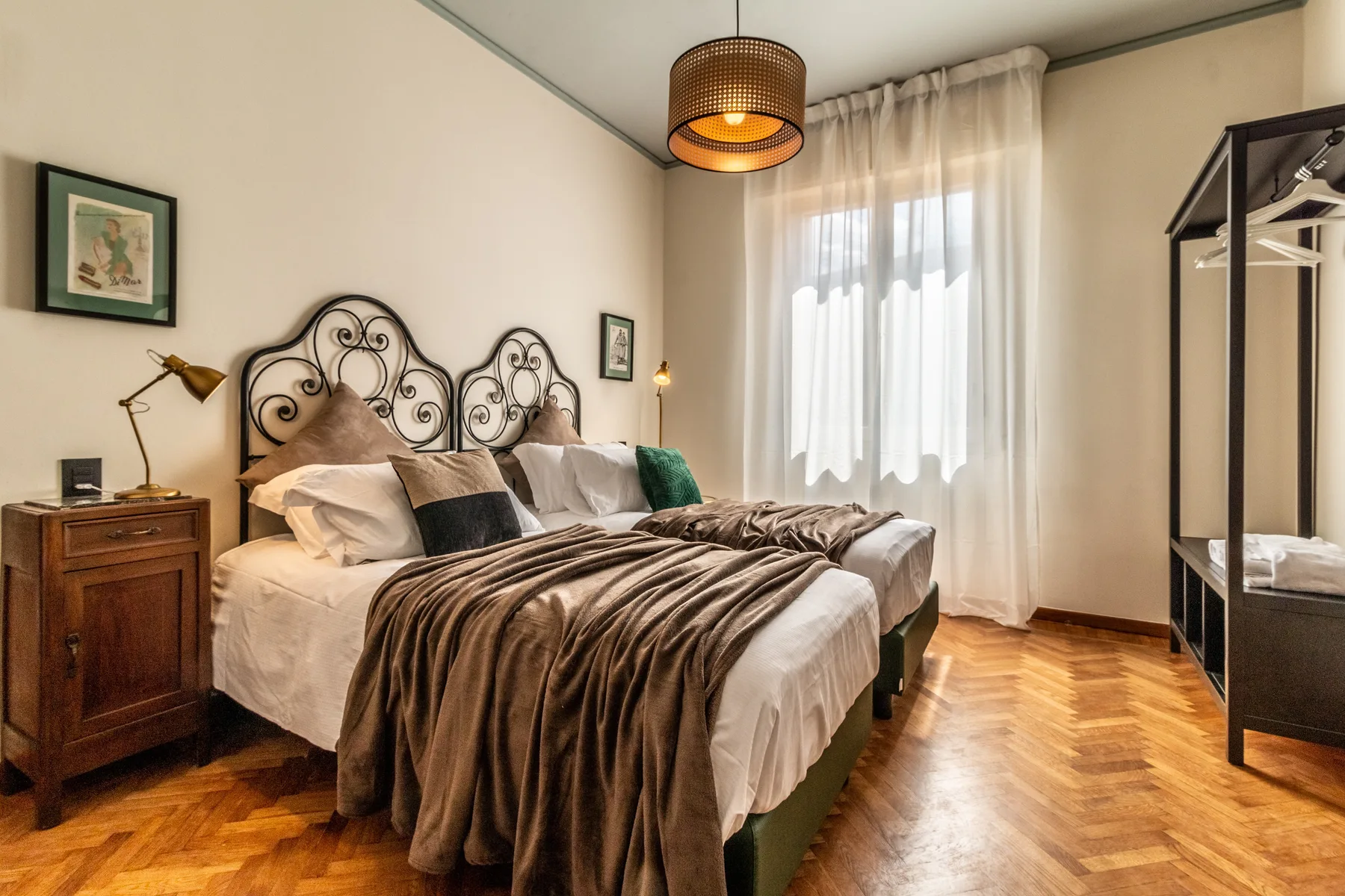 Un dormitorio con una cama doble, mesitas de noche y un armario alto junto a la ventana.