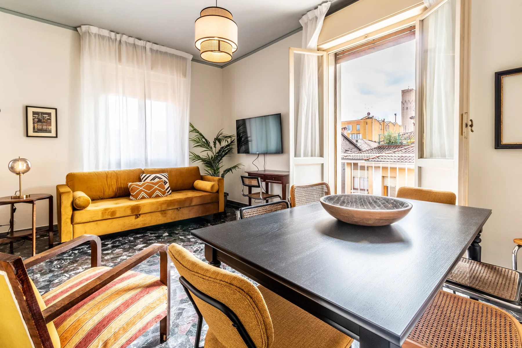 Una luminosa sala de estar con mesa de comedor, asientos y una puerta abierta al balcón.