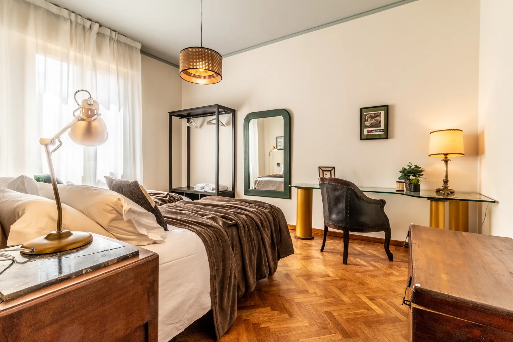 Un dormitorio con cama, escritorio y sillón sobre un suelo de madera.