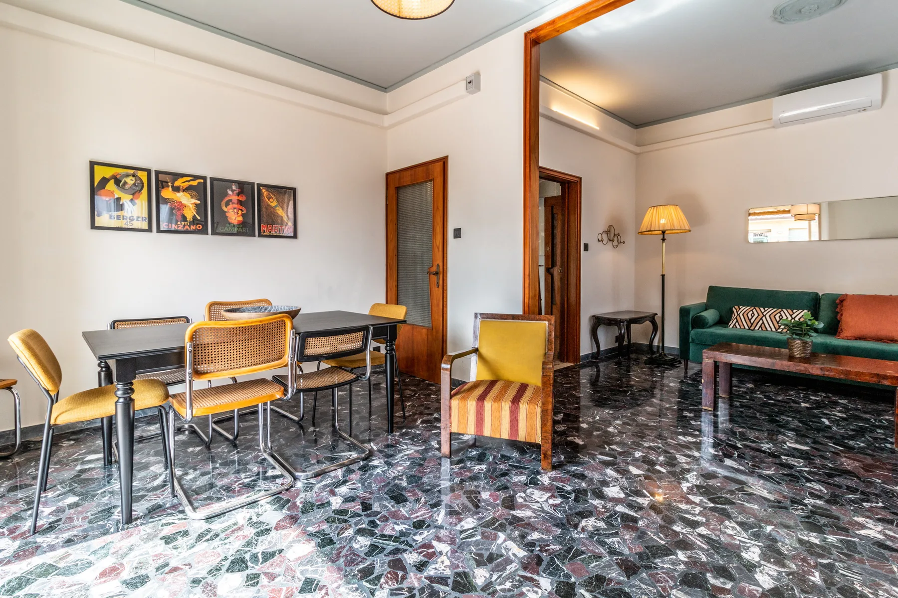 Sala de estar y comedor con una mesa, asientos y un sofá verde.