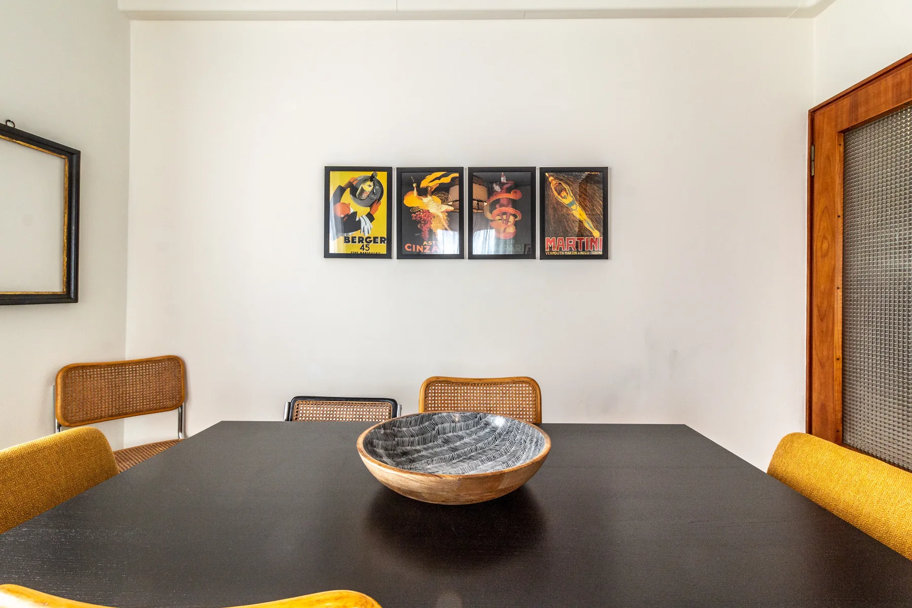 Comedor con una mesa oscura, un cuenco decorativo y cuadros en la pared.