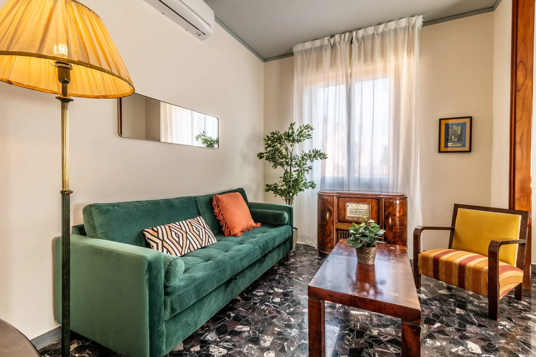 A living room with green seating, a coffee table, and a bright curtained window.