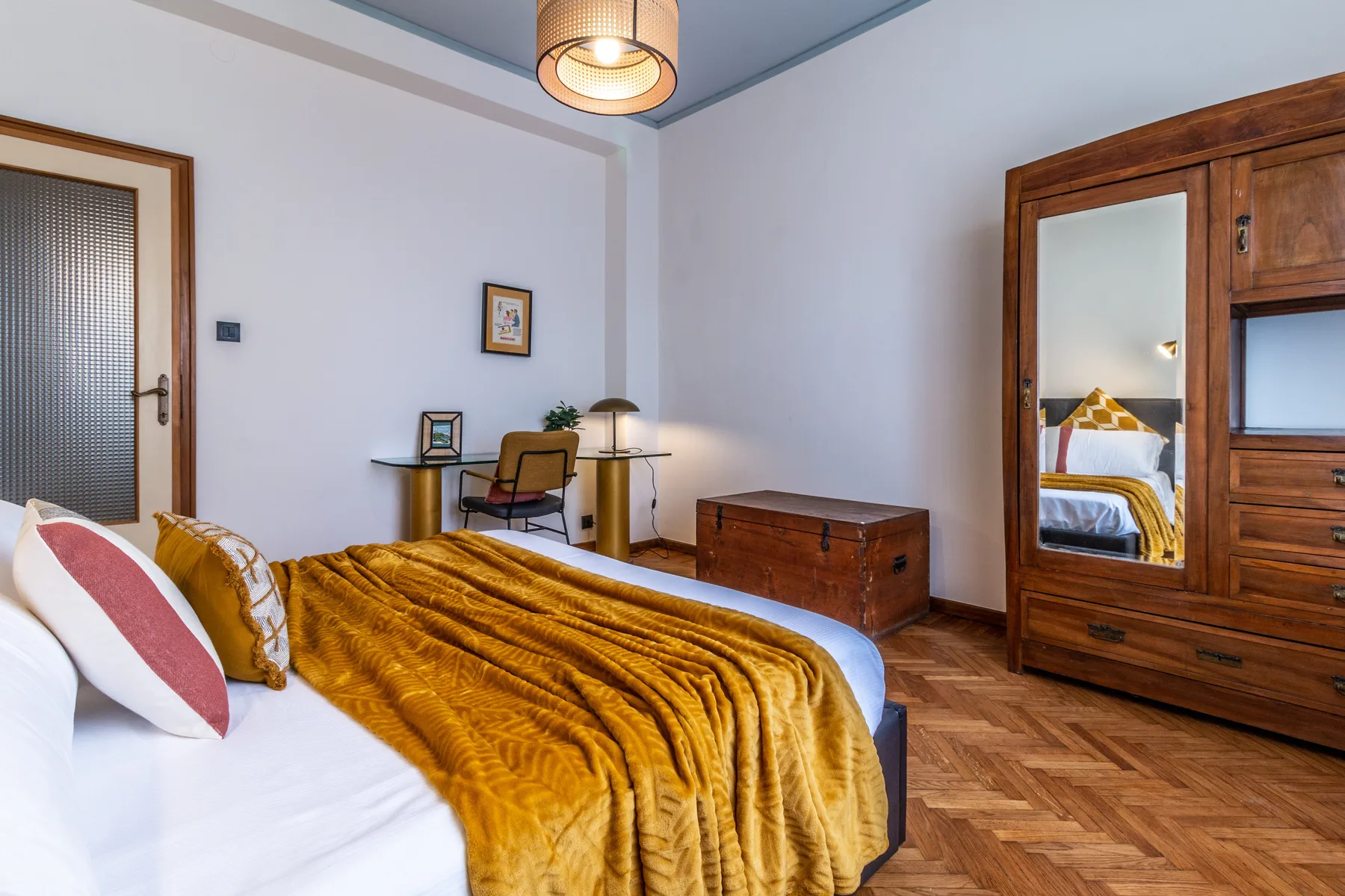 Un dormitorio con una cama cubierta por una manta dorada y un armario de madera.