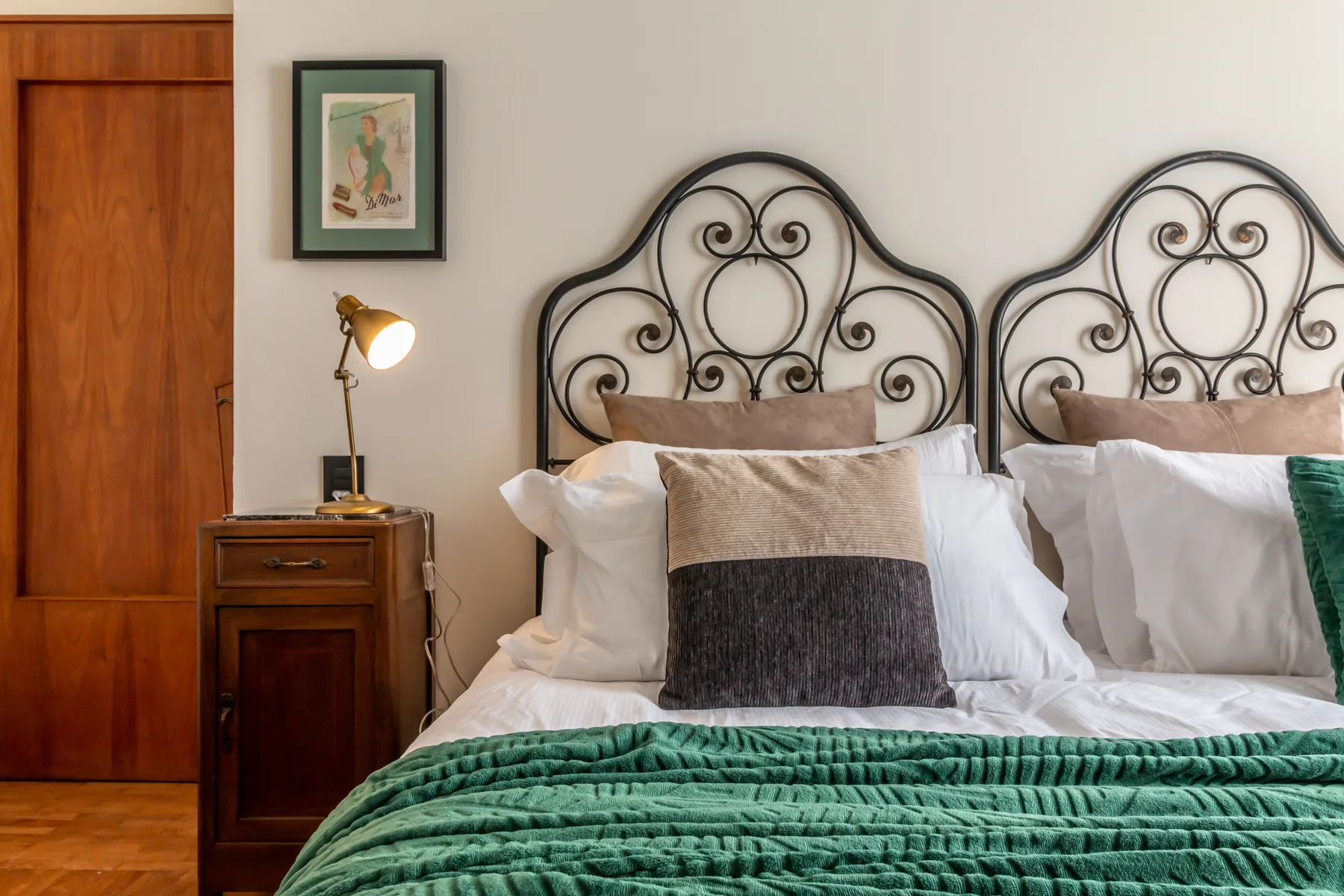 Un dormitorio con dos camas, cabeceros decorativos de metal y una manta verde.