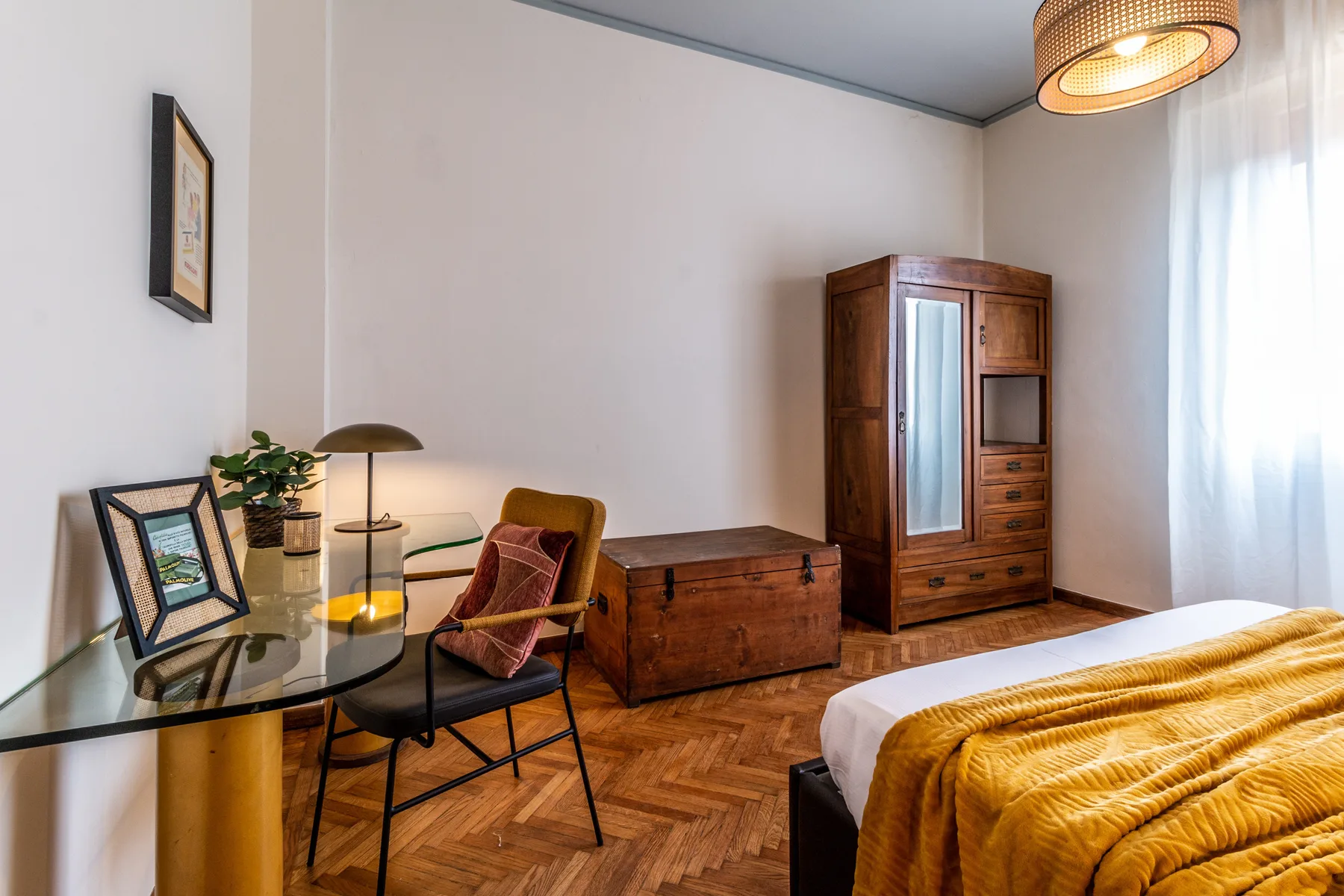 Un dormitorio con escritorio, asiento, muebles de almacenaje de madera y una cama.