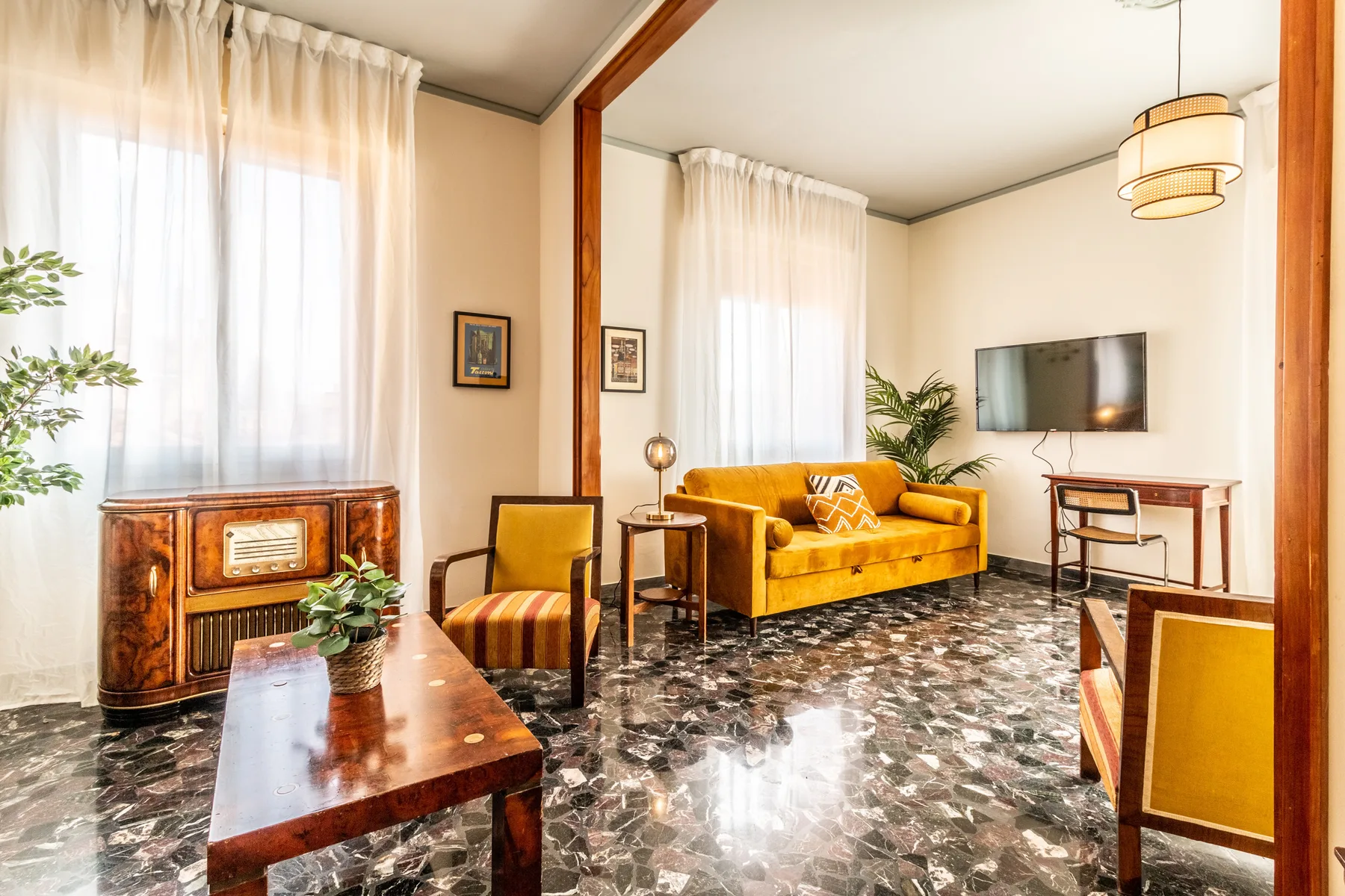 A bright living room with yellow seating and large curtained windows.