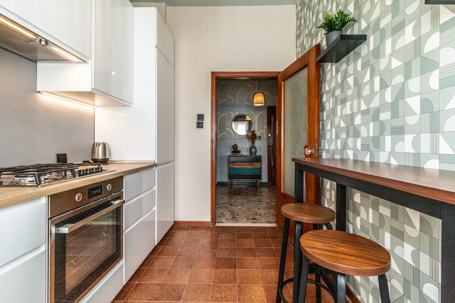 Una cocina con suelo de baldosas, una pared estampada y una barra con taburetes.
