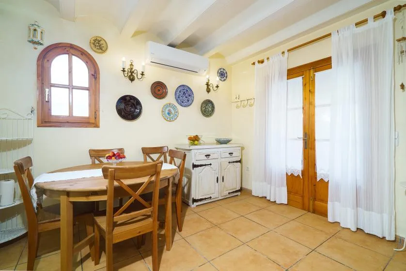 Un comedor con una mesa de madera, sillas y un aparador blanco.