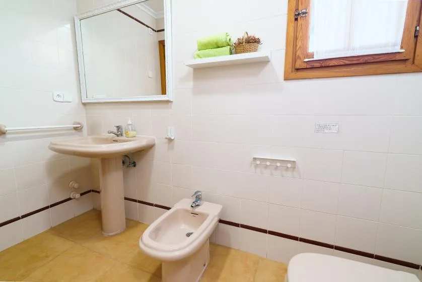 Un baño alicatado con lavabo, bidé y ventana.