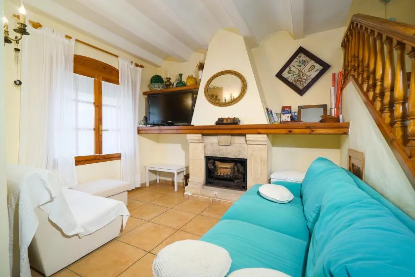 Sala de estar con chimenea, televisor y asientos turquesa.