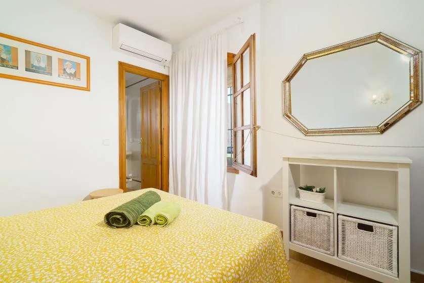 Un dormitorio con una colcha amarilla estampada y toallas verdes.