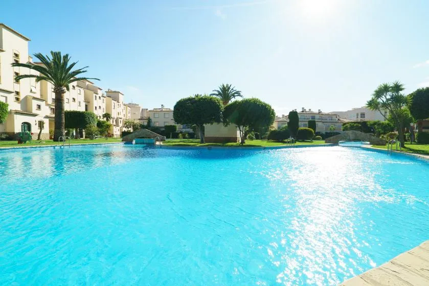 Una gran piscina al aire libre está rodeada de jardines y edificios de apartamentos.
