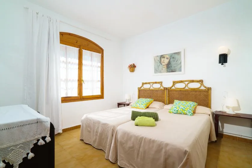 Un dormitorio luminoso con una cama doble y una ventana de arco de madera.