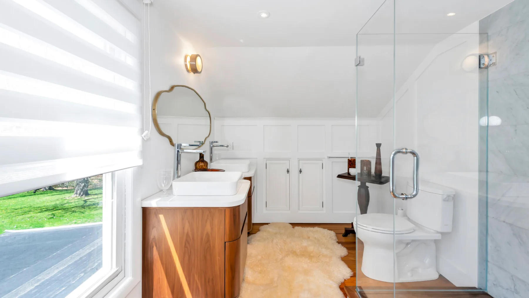 A bright bathroom with a vanity, toilet, and glass shower.
