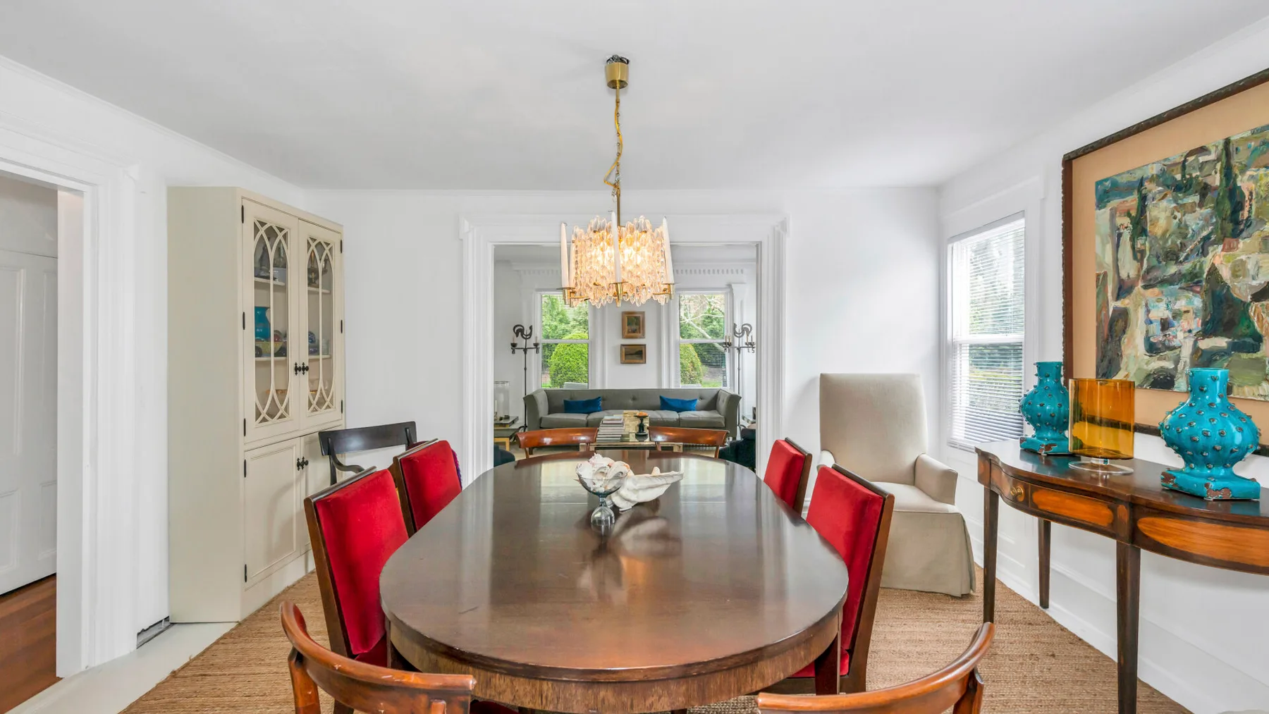 A dining room with a large table, red seating, and a chandelier.