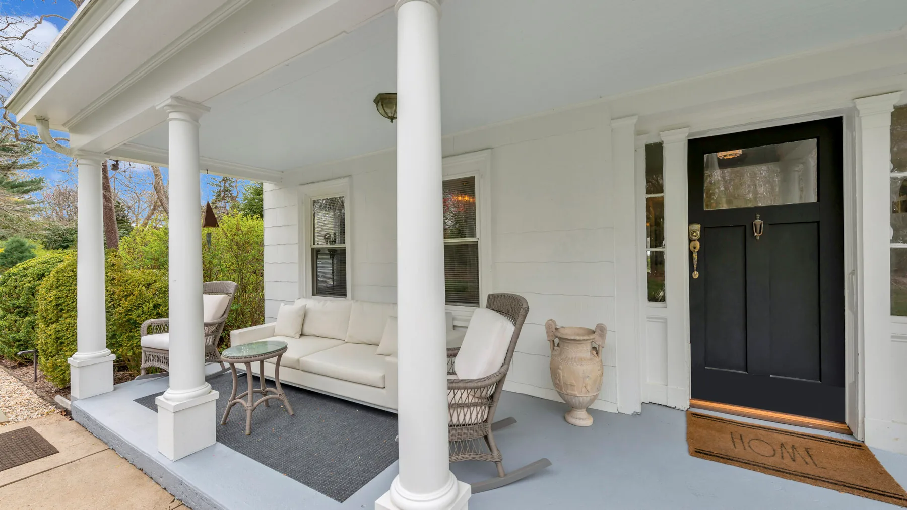 A covered front porch with seating and a dark entry door.