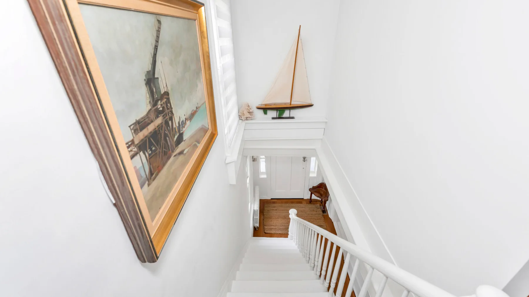 A bright stairwell with white railings and framed artwork on the wall.
