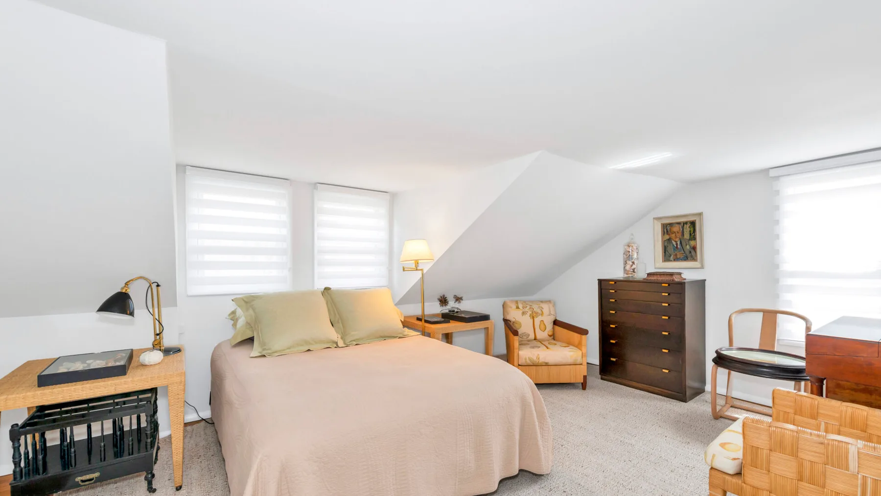 A bedroom with a neatly made bed, a dresser, and a seating area.