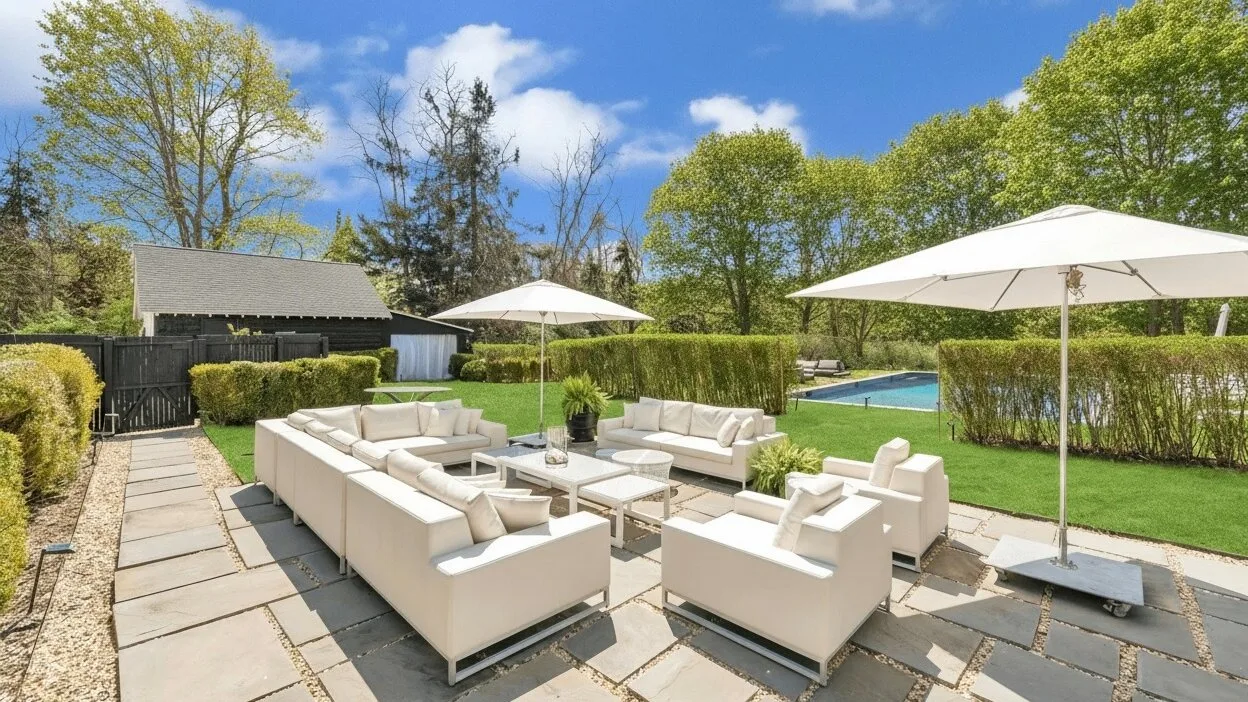 An outdoor patio seating area with light-colored lounge furniture and umbrellas.