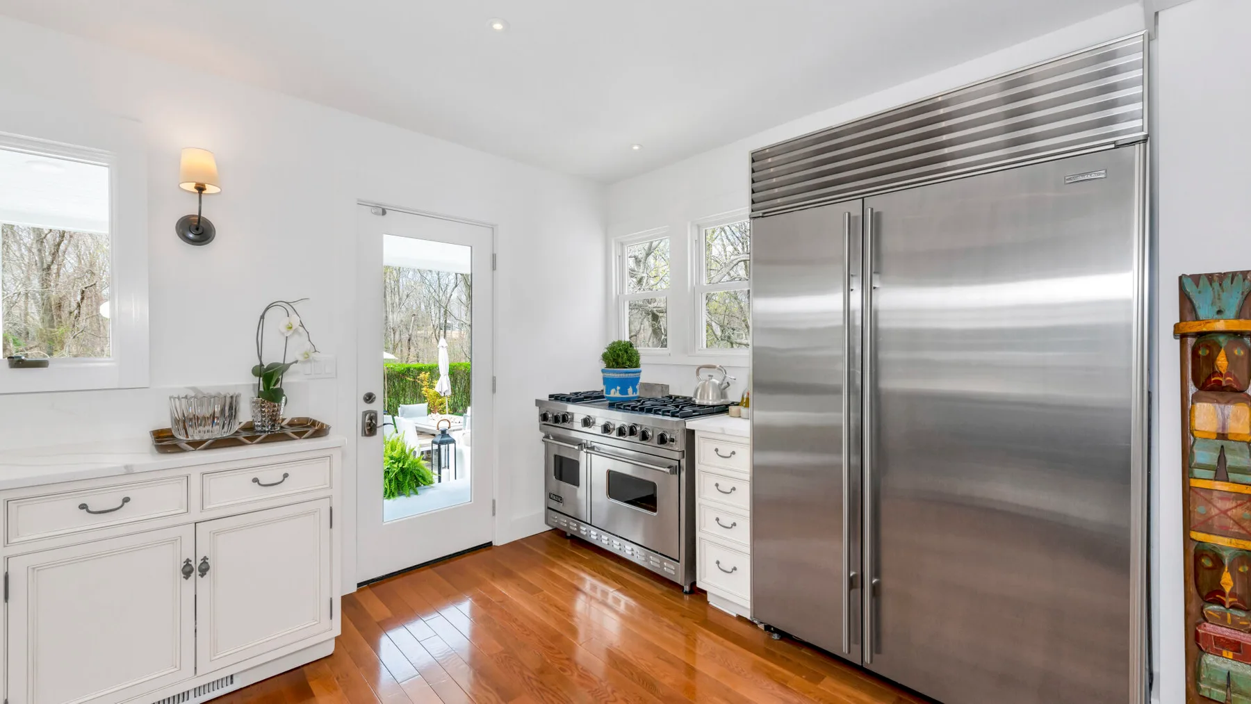 A bright kitchen with stainless steel appliances and polished wood flooring.