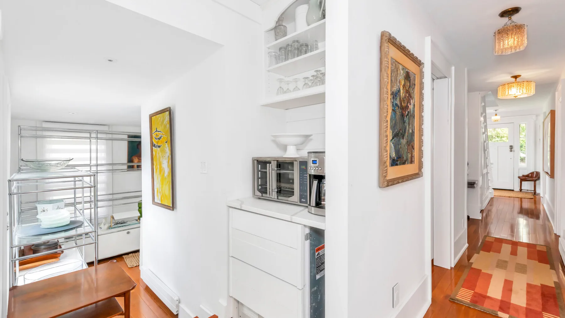 A bright kitchen area with a metal shelving rack and built-in appliances.