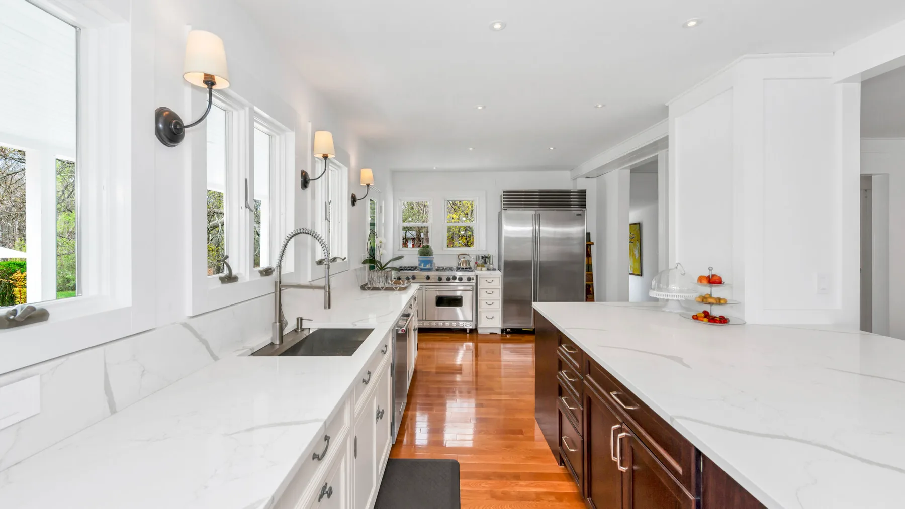 A bright kitchen with white countertops, stainless steel appliances, and a central island.