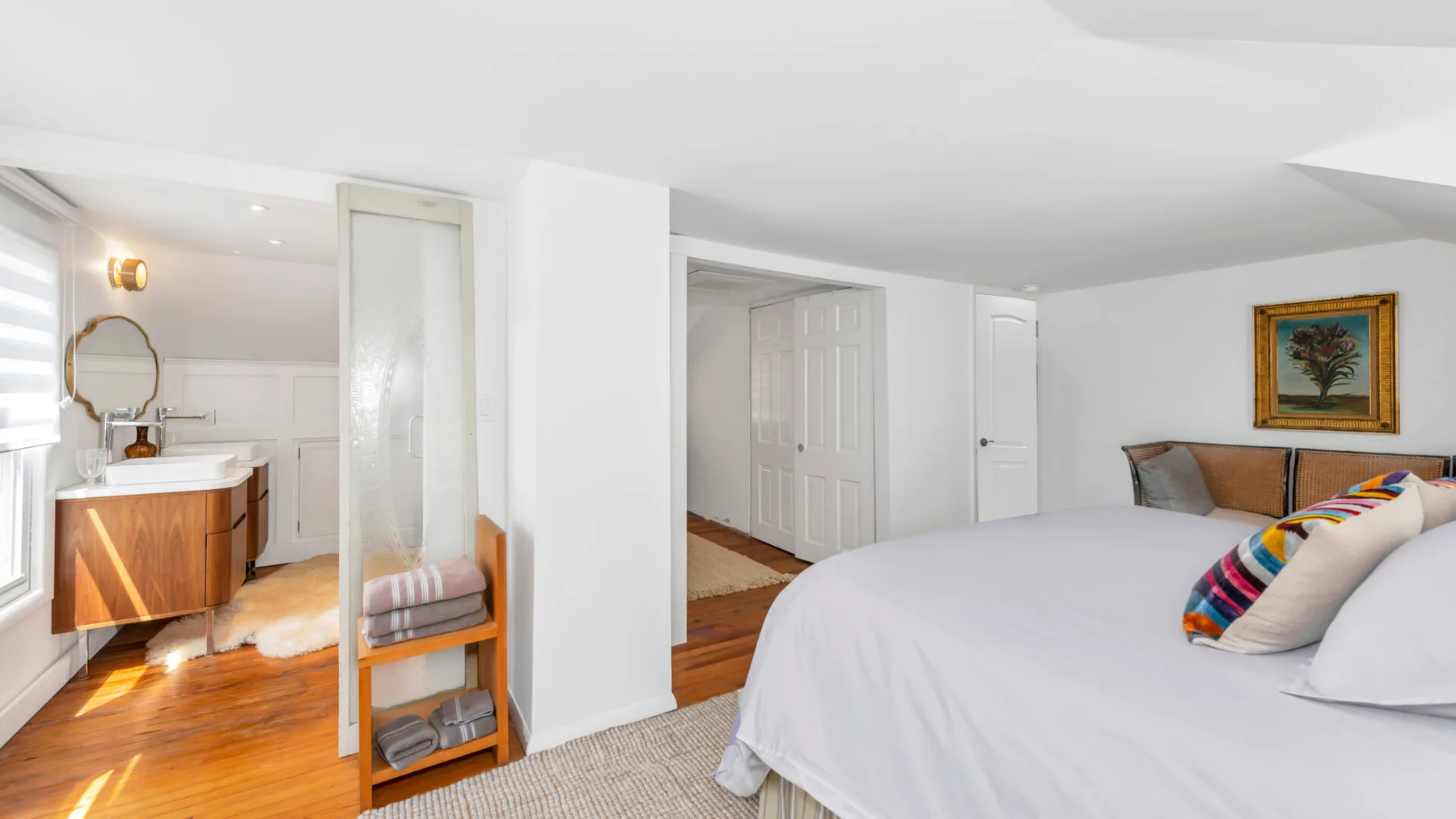 A bedroom with a bed, a vanity, and a doorway.