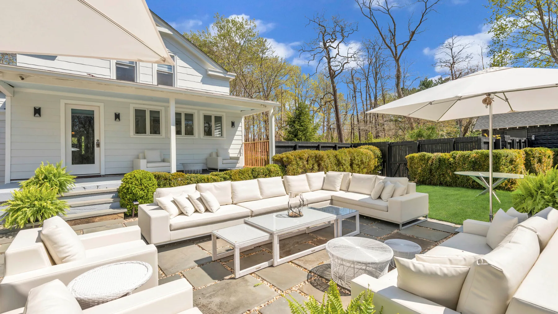 An outdoor patio with light-colored seating and a large shade umbrella.