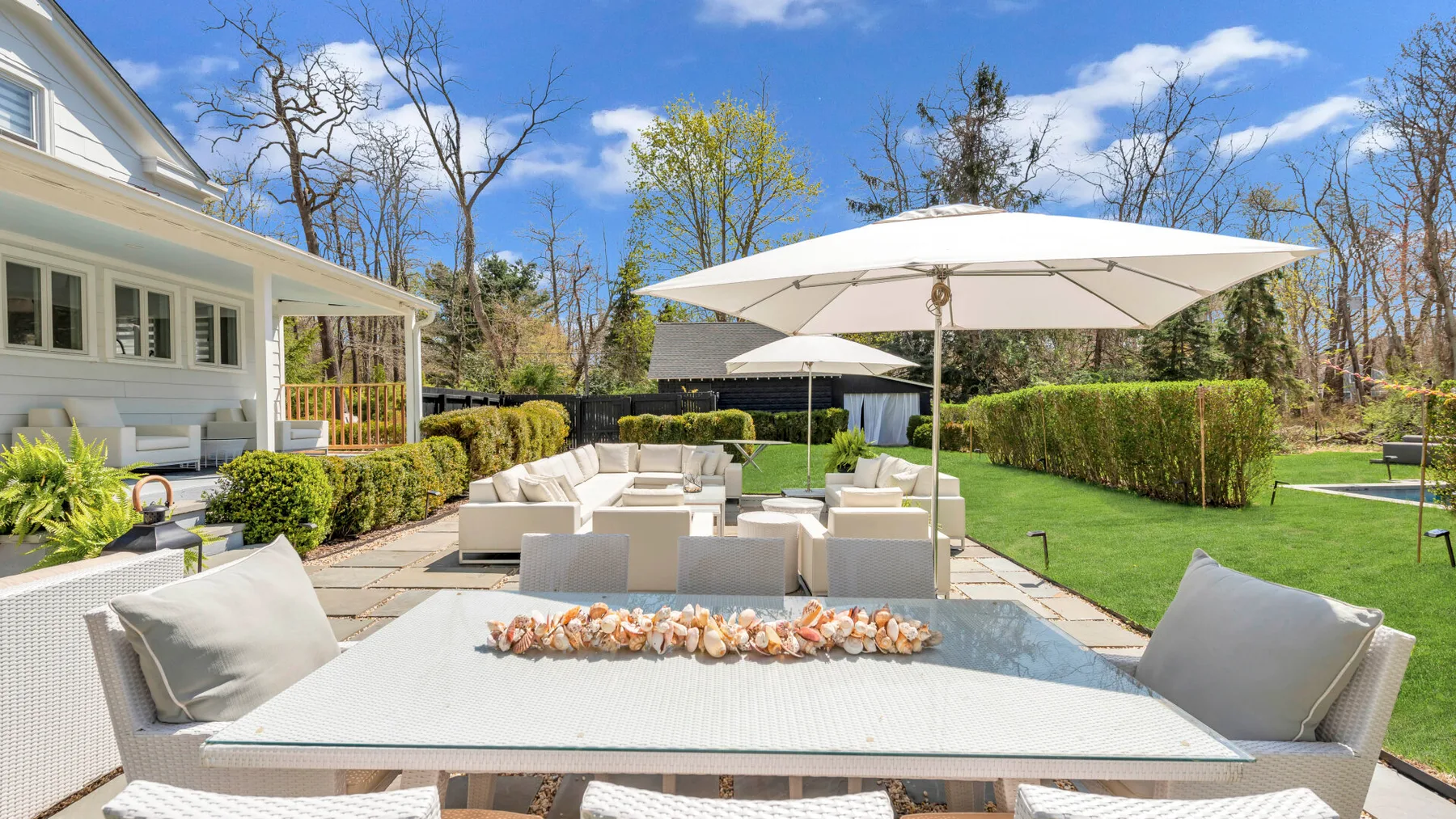 An outdoor patio with a dining table, seating, and a large umbrella.