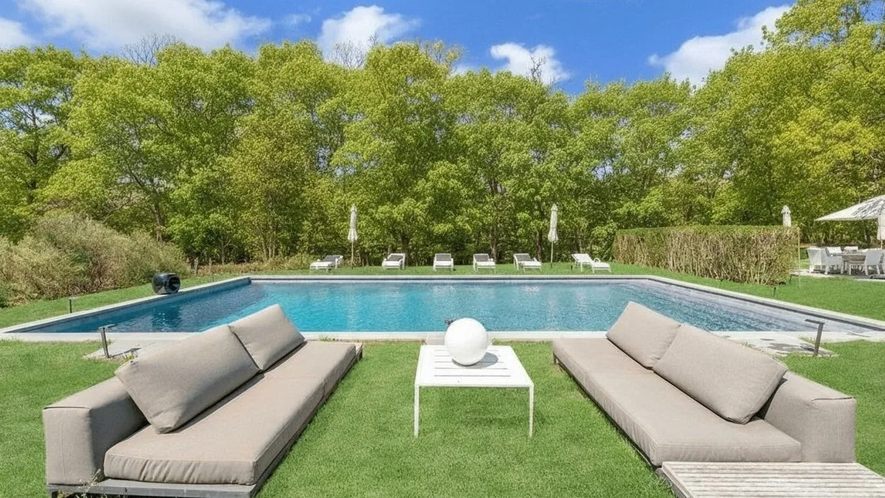 An outdoor poolside seating area with lounge seating on the grass.