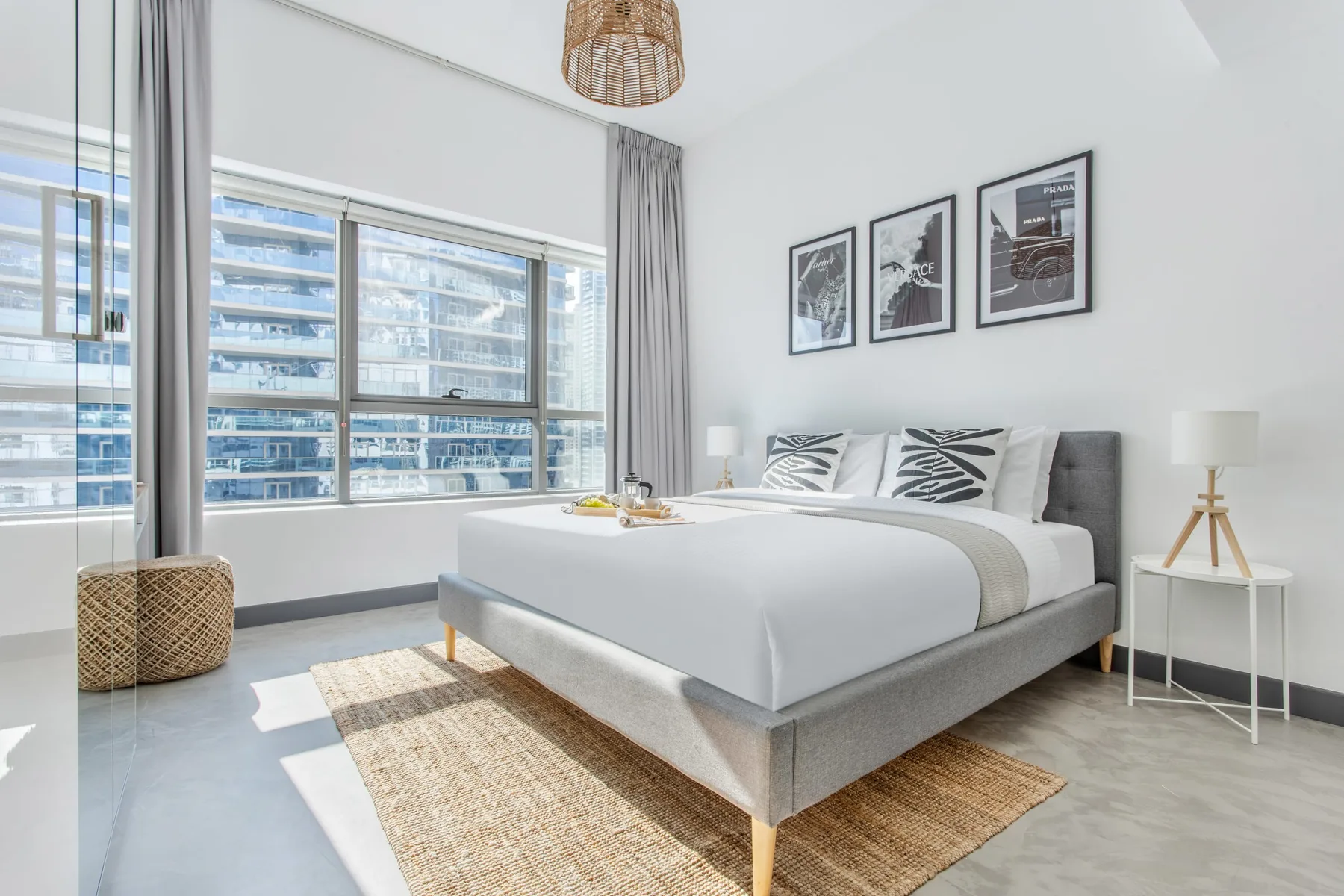 Un dormitorio luminoso con una cama arreglada junto a grandes ventanas.
