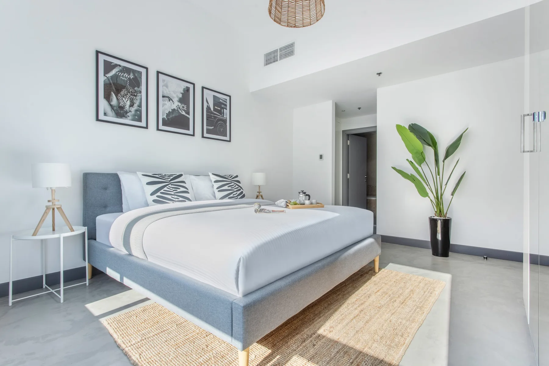 Un dormitorio luminoso con una cama bien tendida y cuadros enmarcados en la pared.
