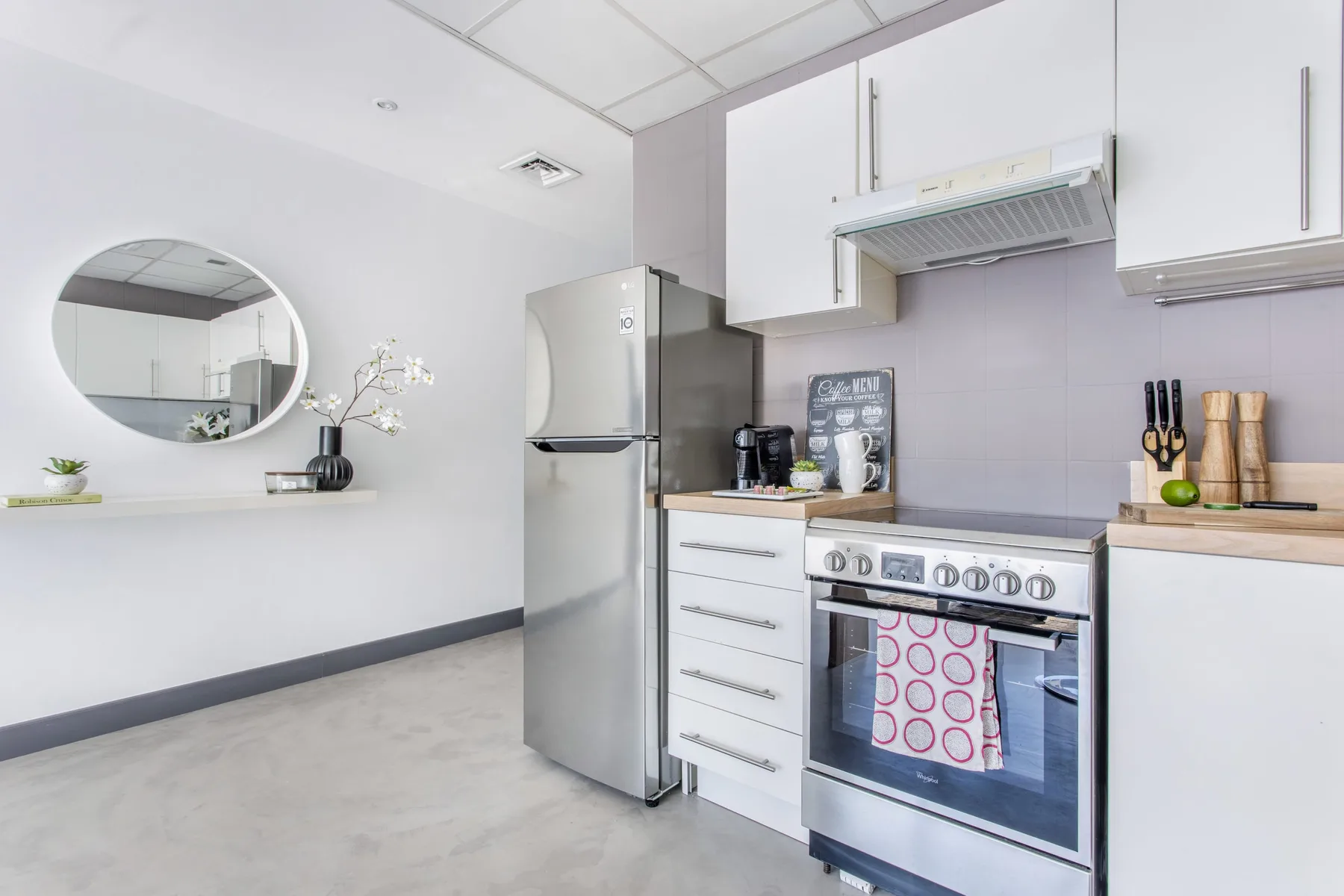 Una cocina luminosa con gabinetes blancos, un refrigerador y una estufa.