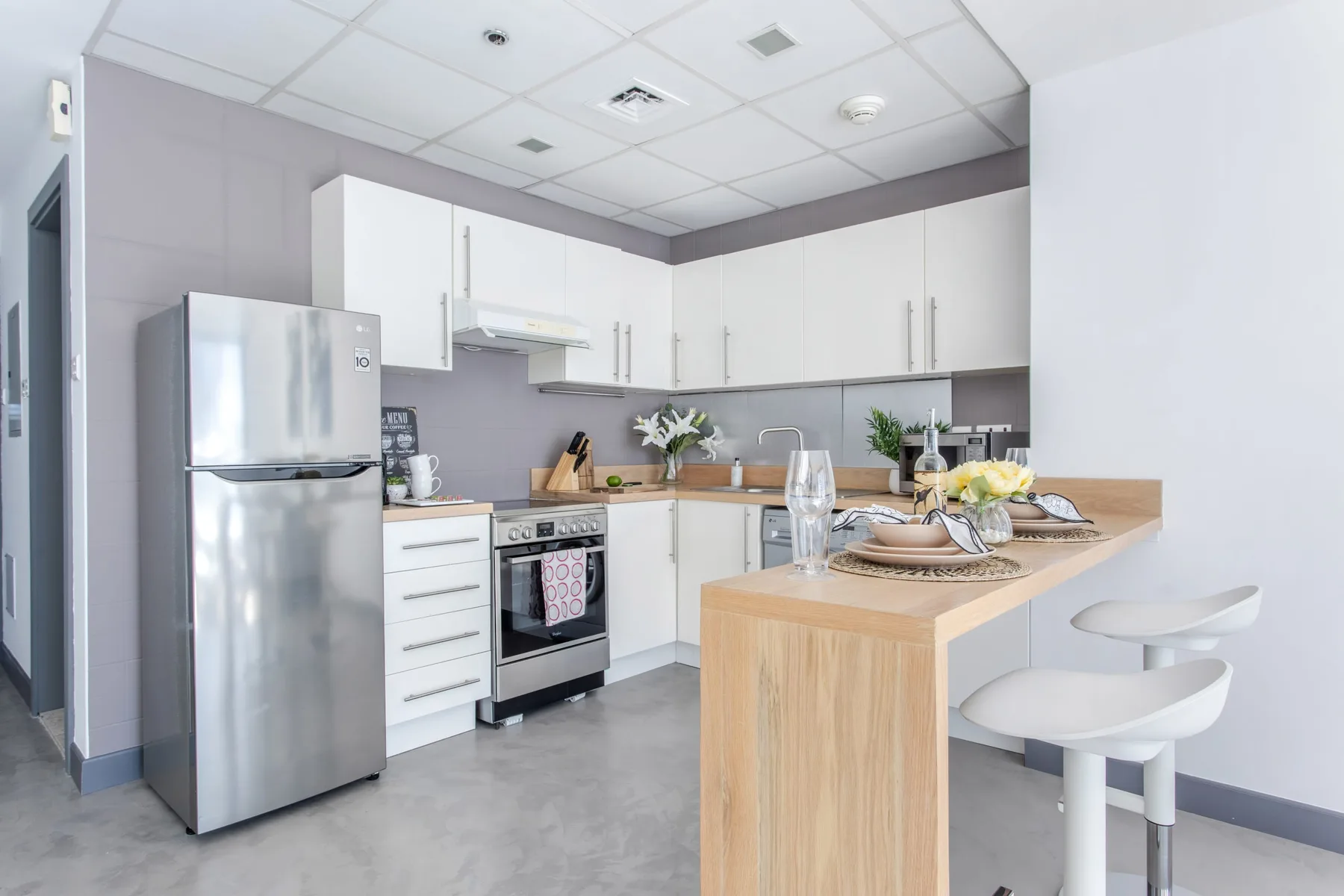Una cocina moderna con gabinetes blancos y una isla con frente de madera.