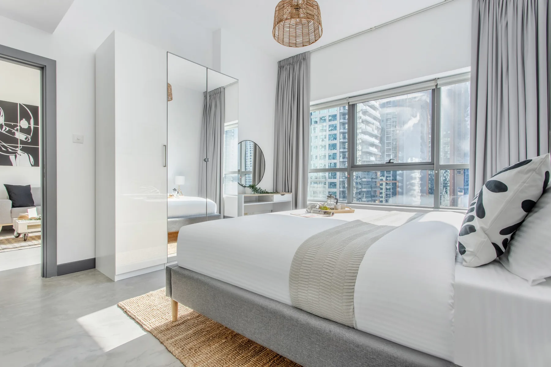Un dormitorio luminoso con una cama hecha junto a grandes ventanas.