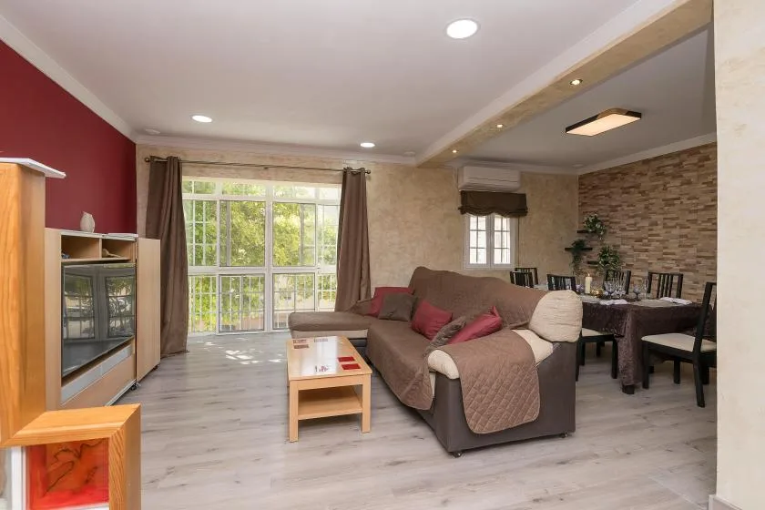 Una sala de estar con una zona de asientos, mesa de centro y ventanales.